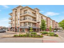 Beautiful exterior view of a multi-story condo building with retail space, lush landscaping, and outdoor seating at 10111 Inverness Main St # 301, Englewood, CO 80112