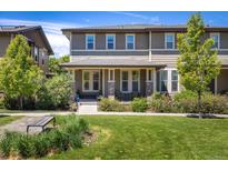 Charming townhome featuring a covered front porch and well-maintained lawn with lush landscaping at 11033 E 28Th Pl, Denver, CO 80238