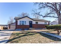 Charming single-story home with brick accents, white siding, a well-kept lawn, and a detached garage at 1024 Malley Dr, Northglenn, CO 80233