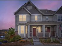 Charming two-story home featuring a cozy front porch, landscaped yard, and a beautiful dusk sky at 3921 E 141St Ave, Thornton, CO 80602
