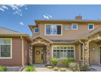 Charming townhome with stone accents, a yellow door, and well-maintained landscaping at 8611 Gold Peak Dr # D, Highlands Ranch, CO 80130