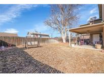 Spacious backyard featuring a covered patio and a charming swing for relaxing outdoors at 5011 Troy St, Denver, CO 80239