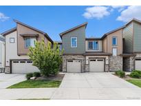 Modern townhome with stone accents, attached garage, and well-maintained landscaping under a blue sky at 9757 Ash Ln, Thornton, CO 80229