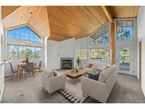 Bright living room with wood ceiling, fireplace, and large windows offering scenic views at 31819 Rocky Village Dr # 301, Evergreen, CO 80439