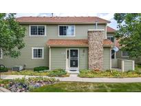 Inviting two-story townhome featuring a stone chimney and well-maintained landscaping at 8406 Everett Way # C, Arvada, CO 80005
