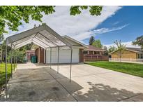 Brick home with an attached garage, concrete driveway with a car port, and well maintained lawn at 13472 E Dakota Ave, Aurora, CO 80012