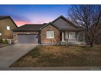 Charming home featuring a stone facade, two-car garage, and well-maintained lawn at dusk at 3966 Aspen Hollow Ct, Castle Rock, CO 80104
