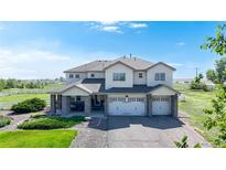 Beautiful two-story home featuring a three-car garage, stone accents, and manicured landscaping at 6051 E 160Th Pl, Brighton, CO 80602