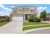 Inviting two-story home featuring a well-maintained lawn, stone accents, and a spacious two-car garage at 1523 Honeysuckle Ct, Brighton, CO 80601