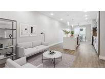 Bright living room and kitchen with an open floorplan, modern furnishings, and hardwood floors at 3500 S Corona St # 409, Englewood, CO 80113