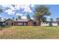 Charming home featuring a stone and wood exterior, a covered porch, and a well-manicured lawn at 25350 Ridge Way, Golden, CO 80401