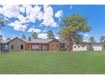 Stunning single-story home featuring stone accents, wood trim, metal roof, large lawn and mature landscaping at 25350 Ridge Way, Golden, CO 80401
