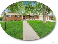 Charming brick home with a well-manicured lawn and mature trees, creating a welcoming curb appeal at 595 W Lake Ave, Littleton, CO 80120