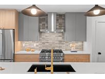 Modern kitchen featuring stainless steel appliances, gray cabinets, and stylish lighting fixtures at 2538 S Acoma St, Denver, CO 80223