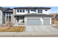 Modern two-story home featuring a three-car garage, stone accents, and a well-manicured lawn at 303 Rogers Ct, Castle Rock, CO 80104