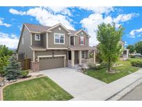 Charming two-story home featuring a well-manicured lawn, covered front porch, and attached two-car garage at 13326 Olive Way, Thornton, CO 80602