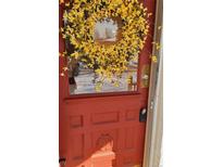 Charming red front door adorned with a vibrant yellow wreath, offering a warm welcome at 3230 Osceola St, Denver, CO 80212