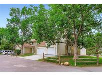 A well-kept townhome with a two-car garage is enhanced by mature trees and a charming wooden fence at 461 S Kalispell Way # D, Aurora, CO 80017