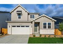 Charming two-story home featuring a neutral color palette, stone accents, well-manicured lawn, and attached two-car garage at 9374 Quartz St, Arvada, CO 80007