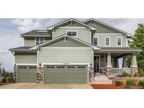 Charming two-story home featuring a two-car garage, covered porch with stone accents and manicured front lawn at 23503 E Minnow Dr, Aurora, CO 80016