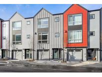 Modern townhomes featuring gray and red exteriors with attached garages on a tree-lined street at 5531 W 11Th Pl, Lakewood, CO 80214