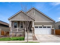 Charming home featuring a well-manicured lawn, white garage door, and inviting front porch at 1056 S Elk Way, Aurora, CO 80018