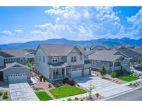 Charming two-story home featuring a landscaped front yard and three-car garage with mountain views in the background at 9551 Eldora St, Arvada, CO 80007