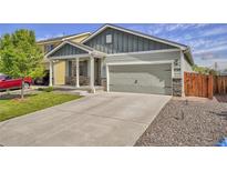 Charming two-story home with a covered porch, a two-car garage, and a well-maintained front yard at 47349 Lily Ave, Bennett, CO 80102