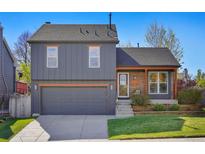 Charming two-story home featuring a well-manicured lawn, a two-car garage, and a cozy brick porch area at 11446 W 105Th Dr, Broomfield, CO 80021