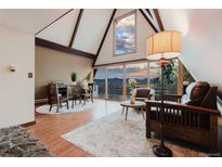 Inviting living room with vaulted ceilings and a wall of windows offering stunning mountain views at 8691 S Warhawk Rd, Conifer, CO 80433