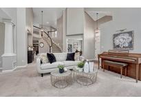 Bright living room with a modern sofa, round tables, piano, and an open staircase to the second floor at 16361 Parkside Dr, Parker, CO 80134