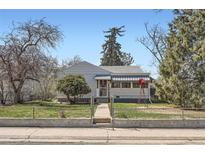 Charming single story home featuring a fenced front yard and a well-maintained lawn, complemented by mature trees at 1997 Newark St, Aurora, CO 80010