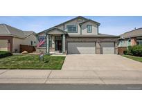 Charming two-story home with a three car garage, landscaped yard, and an American flag at 3418 Oak Leaf Pl, Highlands Ranch, CO 80129