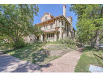 An inviting exterior view shows a well-maintained historic home with a charming brick facade and mature trees at 1000 N Logan St, Denver, CO 80203