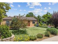 Charming one-story home with a well-manicured lawn, lush landscaping, and a bright red front door at 998 S Leyden St, Denver, CO 80224