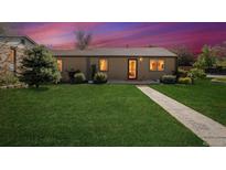 Charming single-story home featuring a well-maintained lawn and inviting walkway to front door at twilight at 998 S Leyden St, Denver, CO 80224