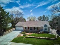 Aerial view of a charming home with a manicured lawn, a lovely front porch, and an attached two-car garage at 5172 S Cody Ct, Littleton, CO 80123
