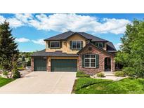 Beautiful two-story home featuring manicured lawn, three-car garage, stone accents, and lush landscaping at 1647 Harris Ct, Erie, CO 80516
