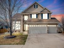 Inviting two-story home with a three-car garage, neutral stucco, and stone accents, all under a colorful evening sky at 14711 Detroit Way, Thornton, CO 80602