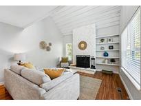 Bright living room with a stone fireplace, built-in shelves, and wood floors at 2645 S Xanadu Way # C, Aurora, CO 80014