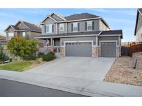 Two-story house with gray siding, stone accents, and a three-car garage at 7478 Oasis Dr, Castle Rock, CO 80108