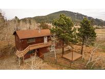 Two-story cabin-style home featuring a charming deck and an outdoor deck on a wooded lot at 26167 De Berry St, Conifer, CO 80433