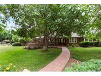 Well-manicured front yard featuring mature tree, lush lawn, and brick walkway leading to a welcoming home at 4 Doral Ln, Littleton, CO 80123