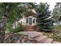 Inviting front entrance with stone walkway and mature trees providing shade and curb appeal at 1425 Autumnwood Ln, Evergreen, CO 80439