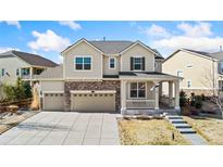Charming two-story home with stone accents, three-car garage and inviting front porch at 23596 E Piccolo Dr, Aurora, CO 80016