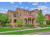 Charming two-story stone home featuring a manicured lawn and inviting covered porch at 9528 Pendio Ct, Highlands Ranch, CO 80126