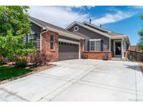 Charming home featuring gray siding, a brick facade, an attached two-car garage, and a well-maintained front yard at 2209 Lupine Pl, Erie, CO 80516