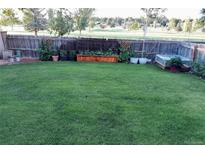 Large, well-maintained backyard featuring a healthy lawn and raised garden beds near a wooden fence at 2844 Troxell Ave, Longmont, CO 80503