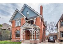 Stunning brick Victorian home with a covered porch, detailed trim, and classic architectural elements at 131 N Sherman St, Denver, CO 80203