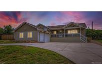 Charming ranch-style home with a welcoming front porch and a two car garage, set against a colorful sunset backdrop at 815 Meadow Ln, Palmer Lake, CO 80133